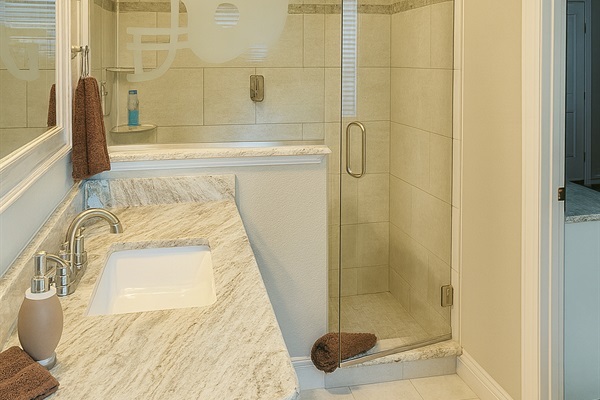 Bright bathroom with granite counters and glass shower enclosure