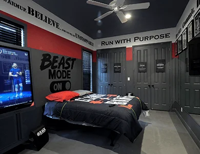 Iron Man Gym Bedroom with workout TV screen, Beast Mode sign, and sports bedding at Lake Louisa Chateau