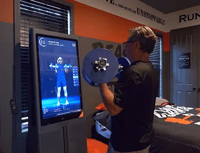 Guest lifting weights in front of workout TV screen in Iron Man Gym Bedroom at Lake Louisa Chateau