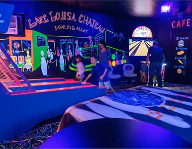 Glow-in-the-dark bowling alley with UV murals and guests playing at Lake Louisa Chateau