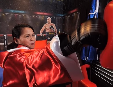 Guest wearing boxing robe and posing with gloves in Boxing Ringside Bedroom at Lake Louisa Chateau