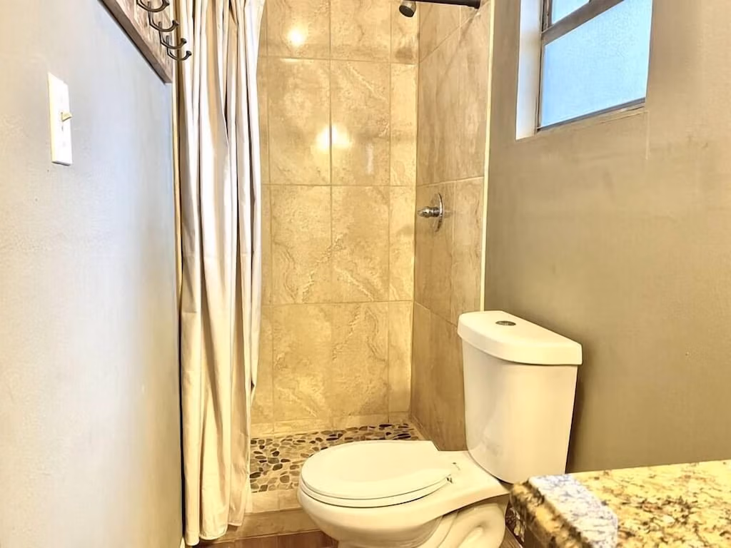 Guest house bathroom with tile shower and pebble floor in Blue Room at Clear Lake Casa, Florida