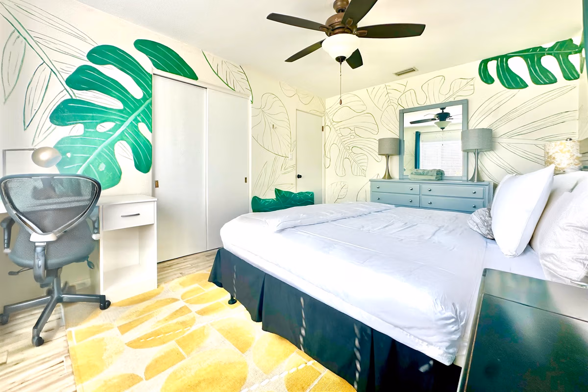 Tropical leaf mural bedroom with navy bed and teal dresser in Downstairs Tropic Room at Jessamine Dream